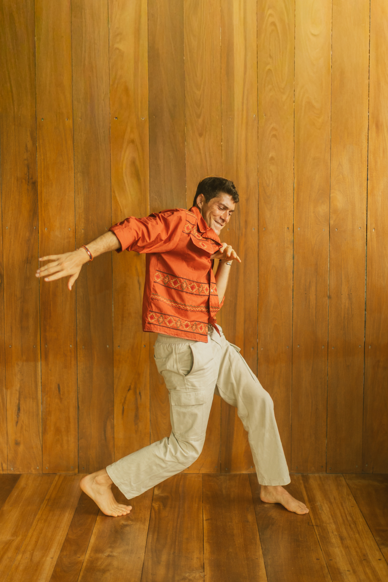 Adam barefoot and dancing against a wood wall
